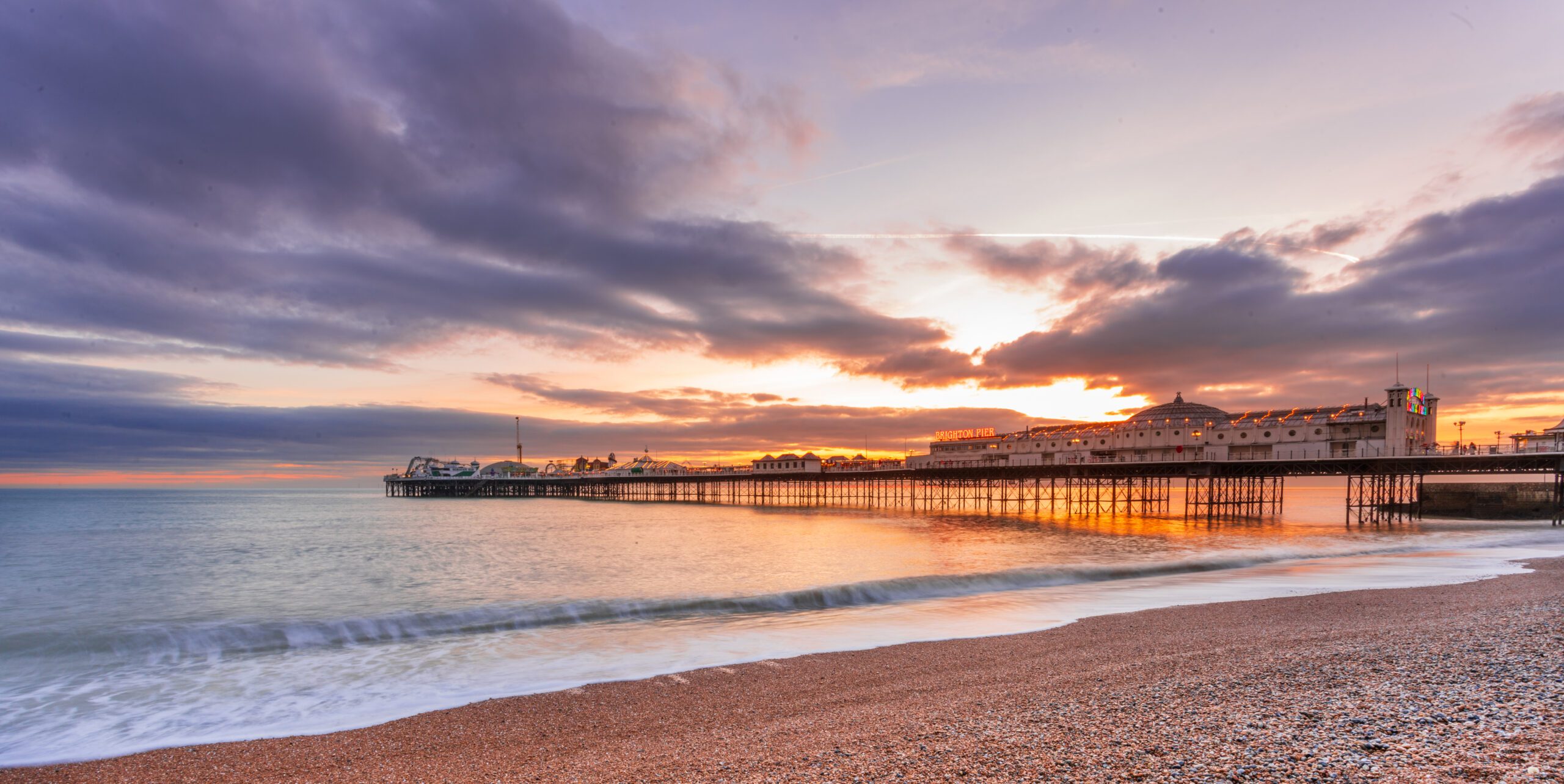A peaceful view of Brighton beach at sunset, with gentle waves touching the pebbled shore. Life is beautiful